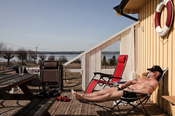 An inmate sentenced to sixteen and a half years for murder and narcotics related crime is seen sun bathing in front of the wooden cottage where he lives in Bastoy Prison