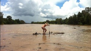 A naked man braves the croc on a log